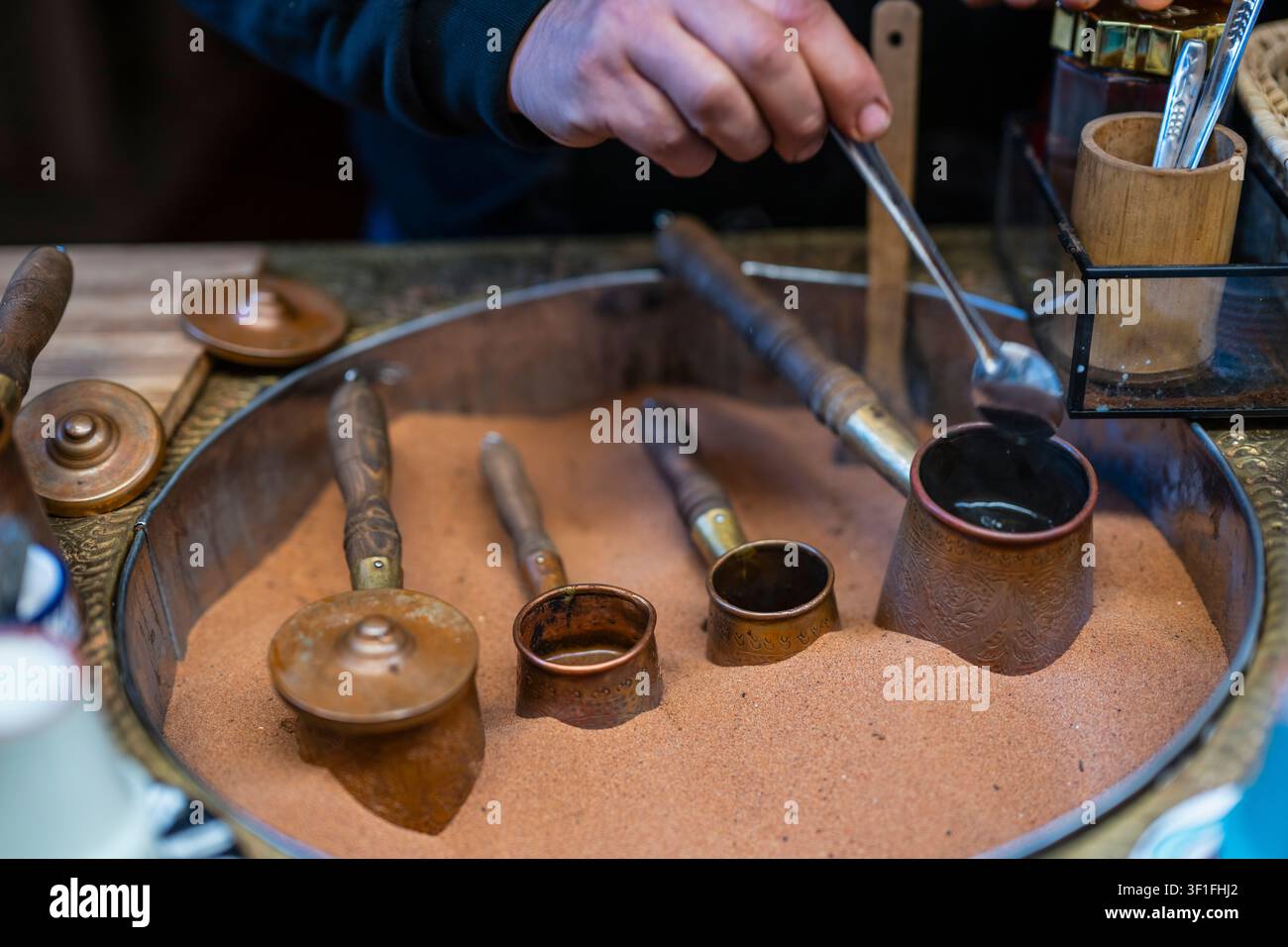 Uomo che prepara un caffè turco tradizionale nella sabbia calda Foto Stock