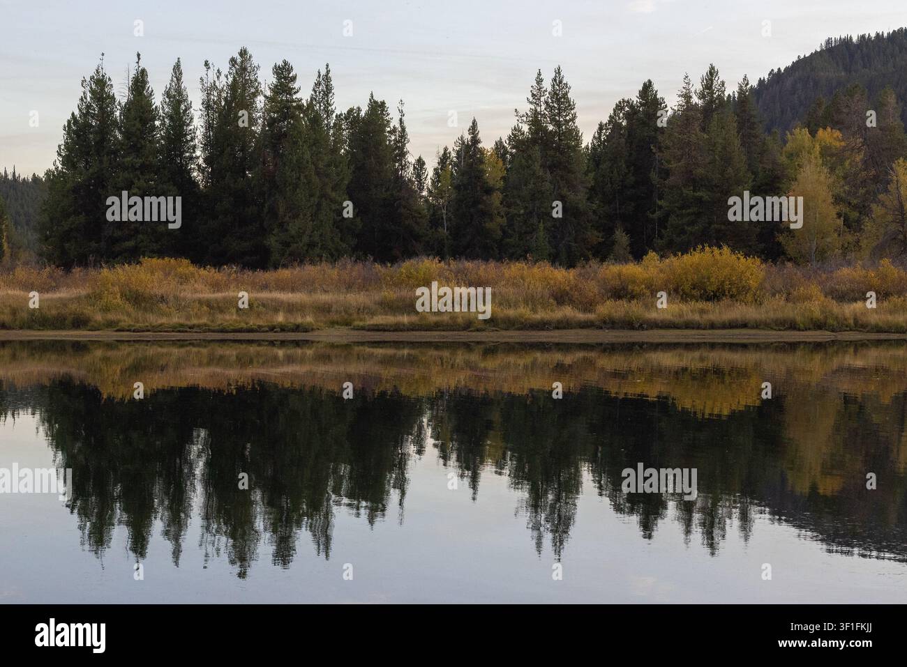 Riflessi di una foresta autunnale su un lago di montagna calmo al crepuscolo Foto Stock