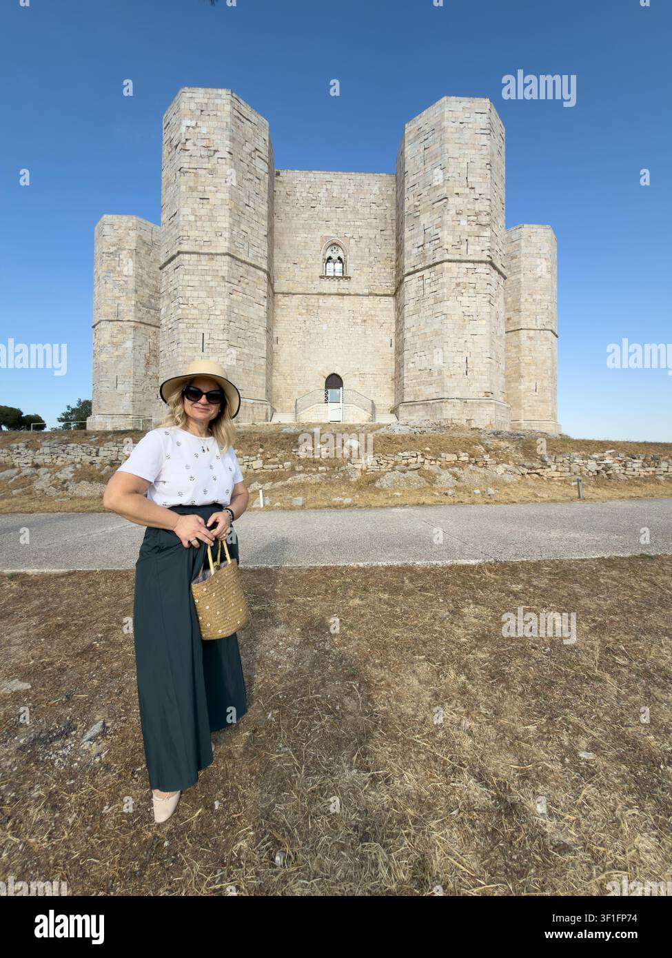 Un visitatore adulto posa davanti alla facciata ottagonale monumentale del Castel del Monte vicino ad Andria, Puglia, Italia. Foto Stock