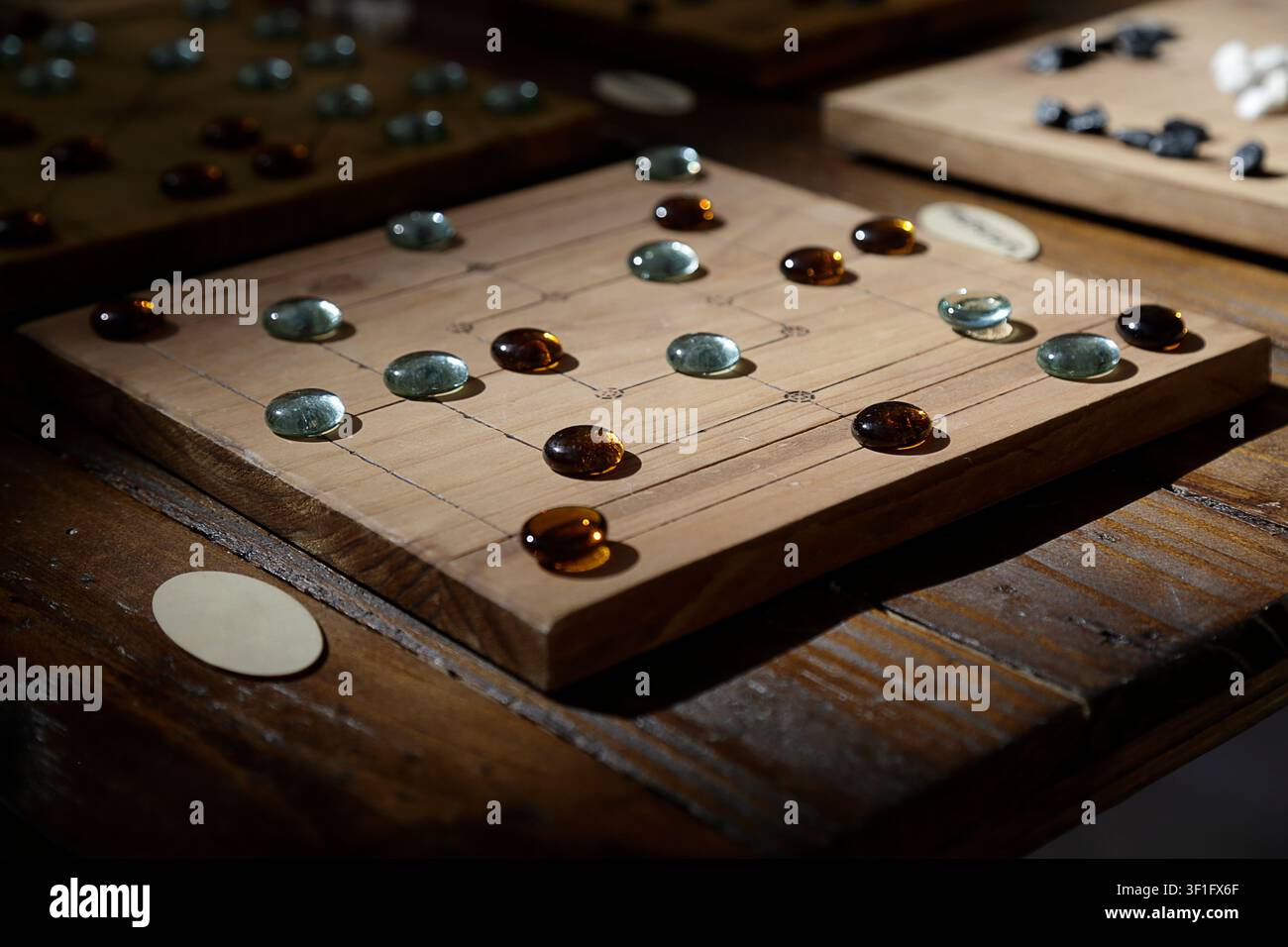 Gioco da tavolo in legno artigianale con pezzi di gioco in vetro disposti su una griglia incisa. Foto Stock