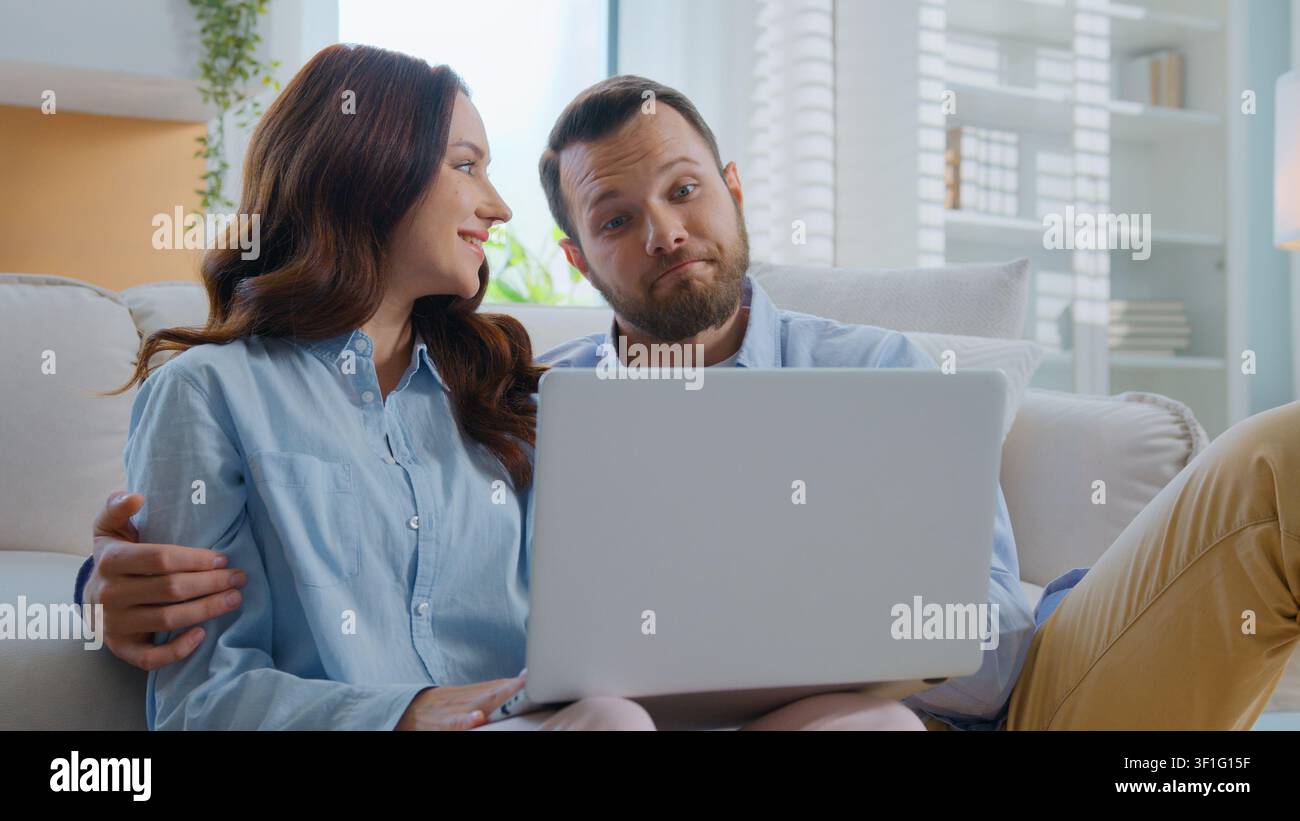 Famiglia caucasica felice che guarda il laptop, abbracciandosi, coccolandosi, parlando, scegliendo beni e-commerce, facendo acquisti su internet insieme, uomo e donna che si abbracciano, parlano Foto Stock