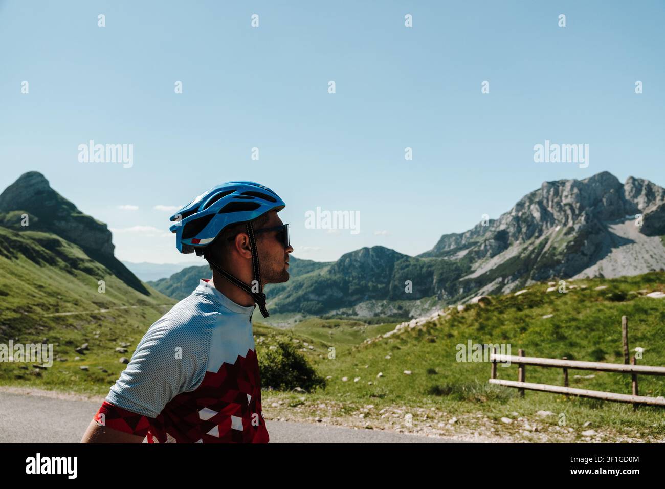 Ciclista con casco si ferma ad ammirare il paesaggio alpino al Passo Sedlo nel Parco Nazionale del Durmitor, Montenegro. Il paesaggio montano si estende sotto un Foto Stock
