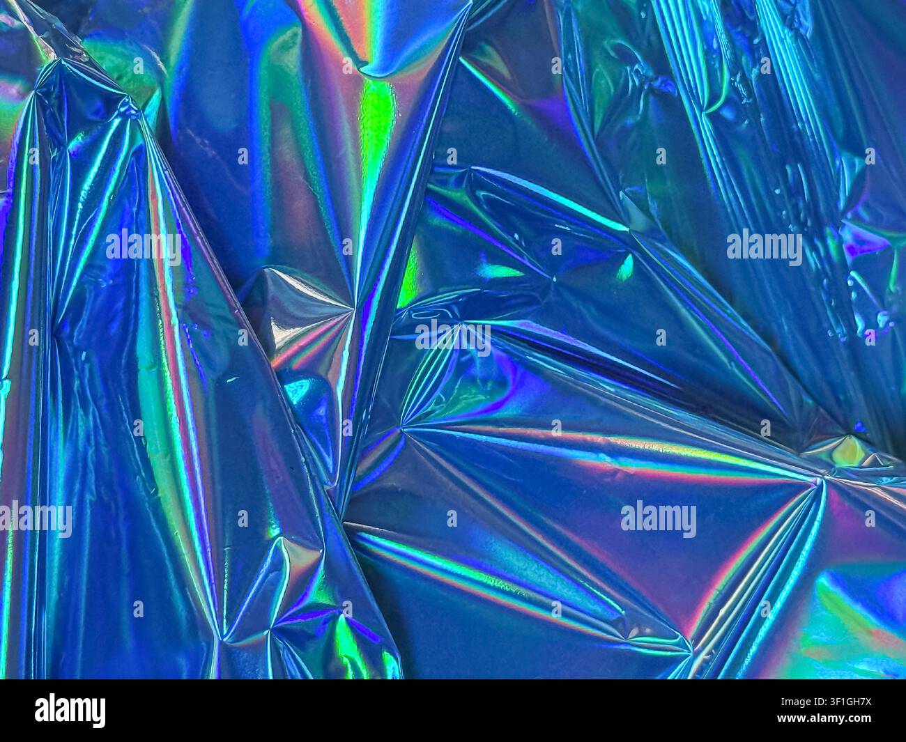 Vista ravvicinata astratta di materiale olografico blu accartocciato. La superficie riflettente mostra colori iridescenti vibranti e pieghe geometriche nette ill Foto Stock