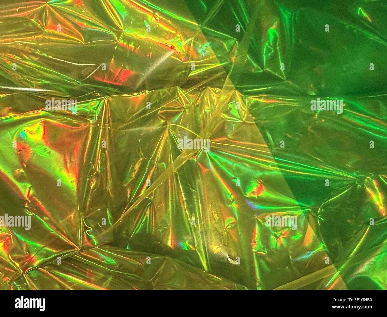 Primo piano di una pellicola olografica accartocciata che crea colori vivaci arcobaleno ed effetti scintillanti. Transizione sfumata liscia da giallo a verde. Perfetto Foto Stock
