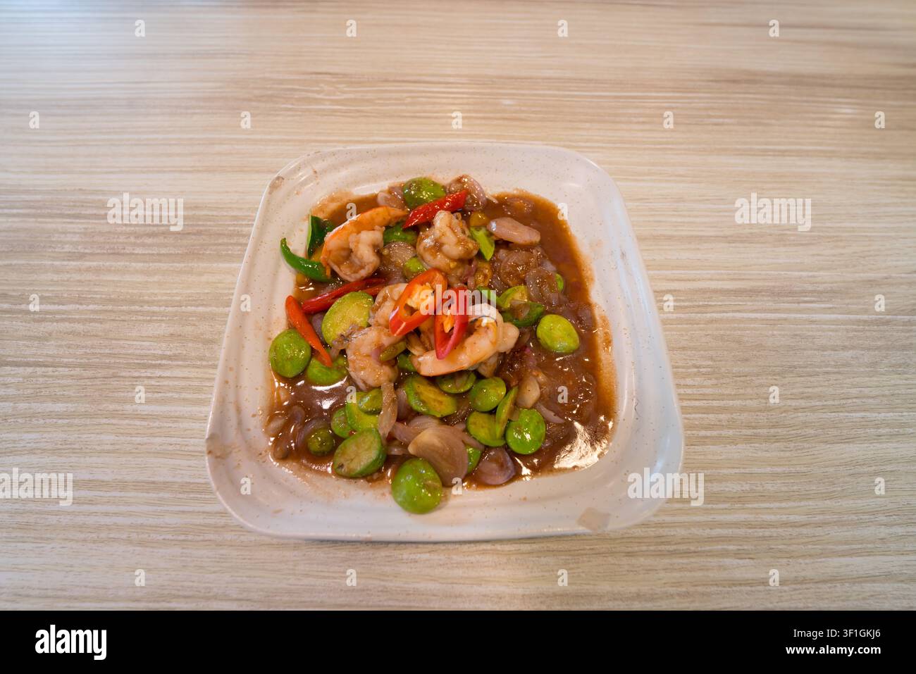 Un fagiolo puzzolente saltato in padella, cibo locale thailandese sul tavolo Foto Stock