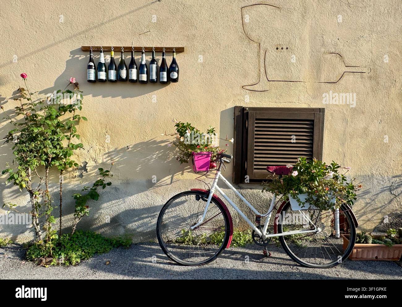 Bicicletta e bottiglie di vino vuote usate come decorazione fuori dal ristorante a Serralunga d'Alba Langhe Piemonte Italia Foto Stock