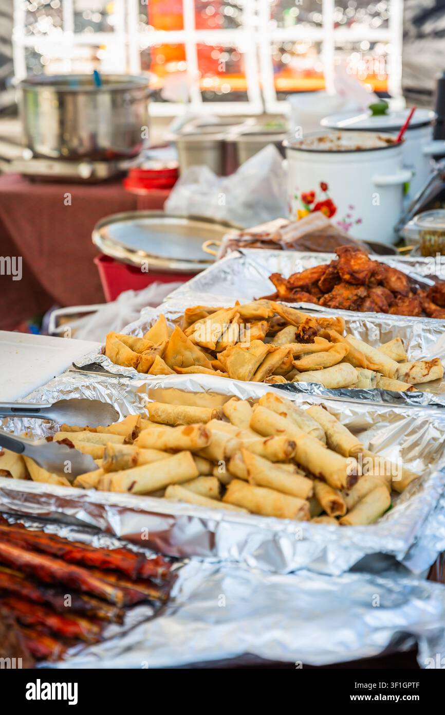 Deliziose spring roll fritte e samosas servite a una bancarella di cibo all'aperto Foto Stock