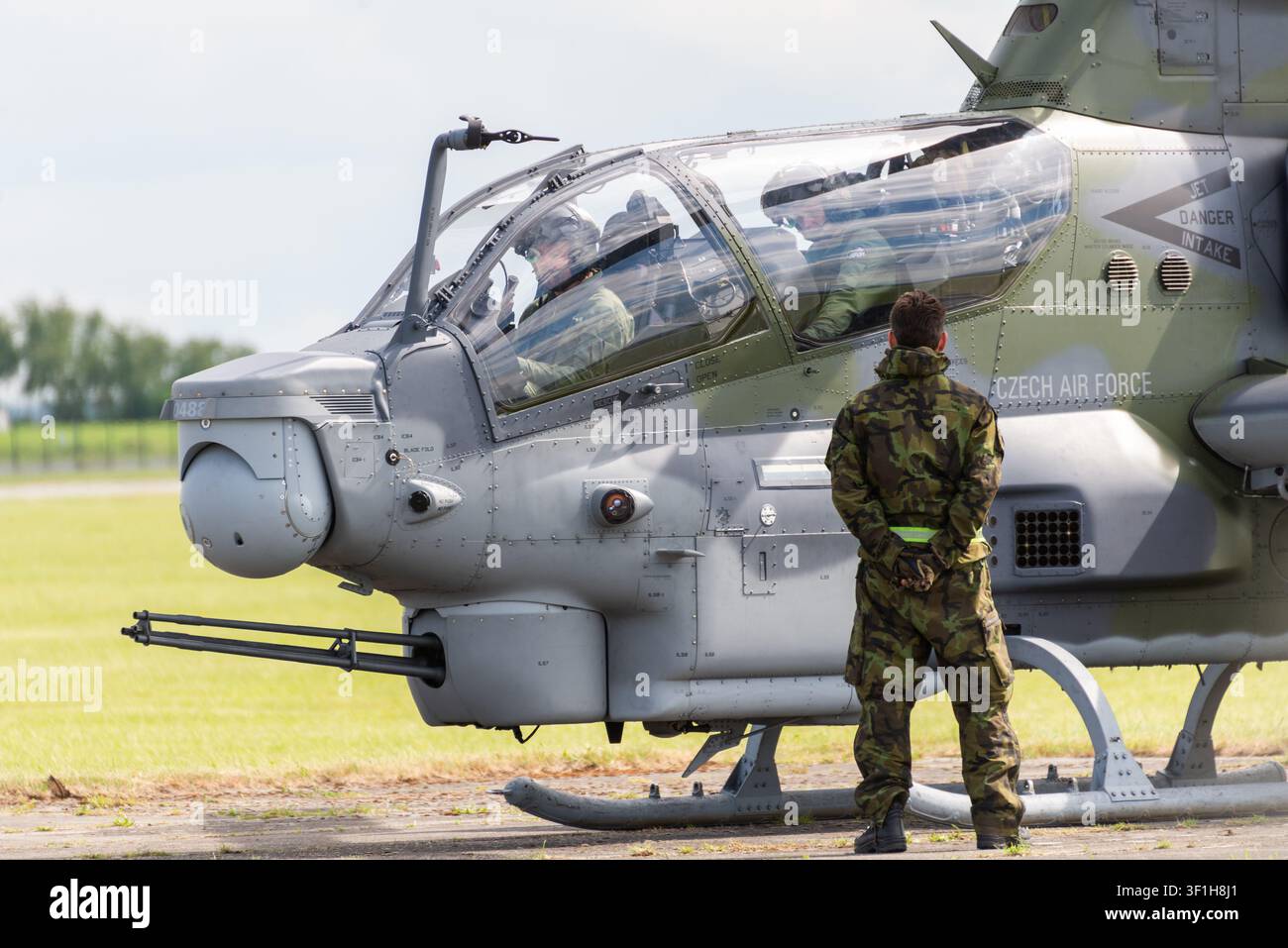 Soldato dell'esercito ceco in piedi accanto a un elicottero da combattimento Bell AH-1Z Viper su un campo d'aviazione erboso durante una mostra aerea militare Foto Stock
