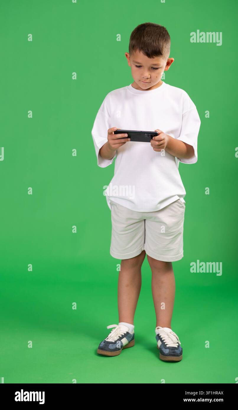 Bambino in età prescolare gioca a giochi online o scorre sullo smartphone Foto Stock