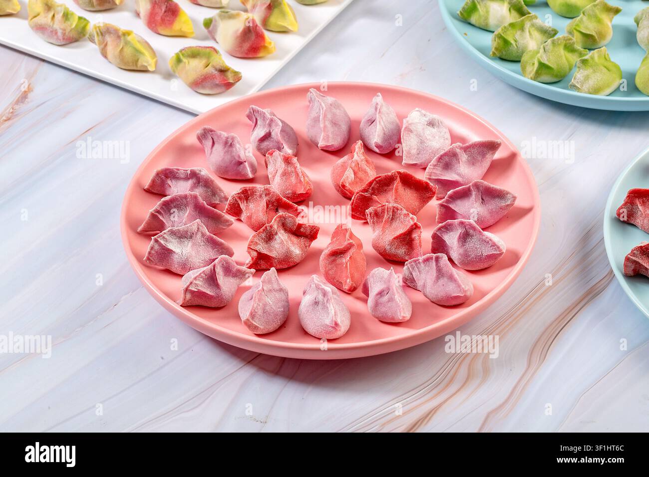 Dumplings di verdure colorati crudi e freschi su piatti, Jiaozi cinesi congelati Foto Stock