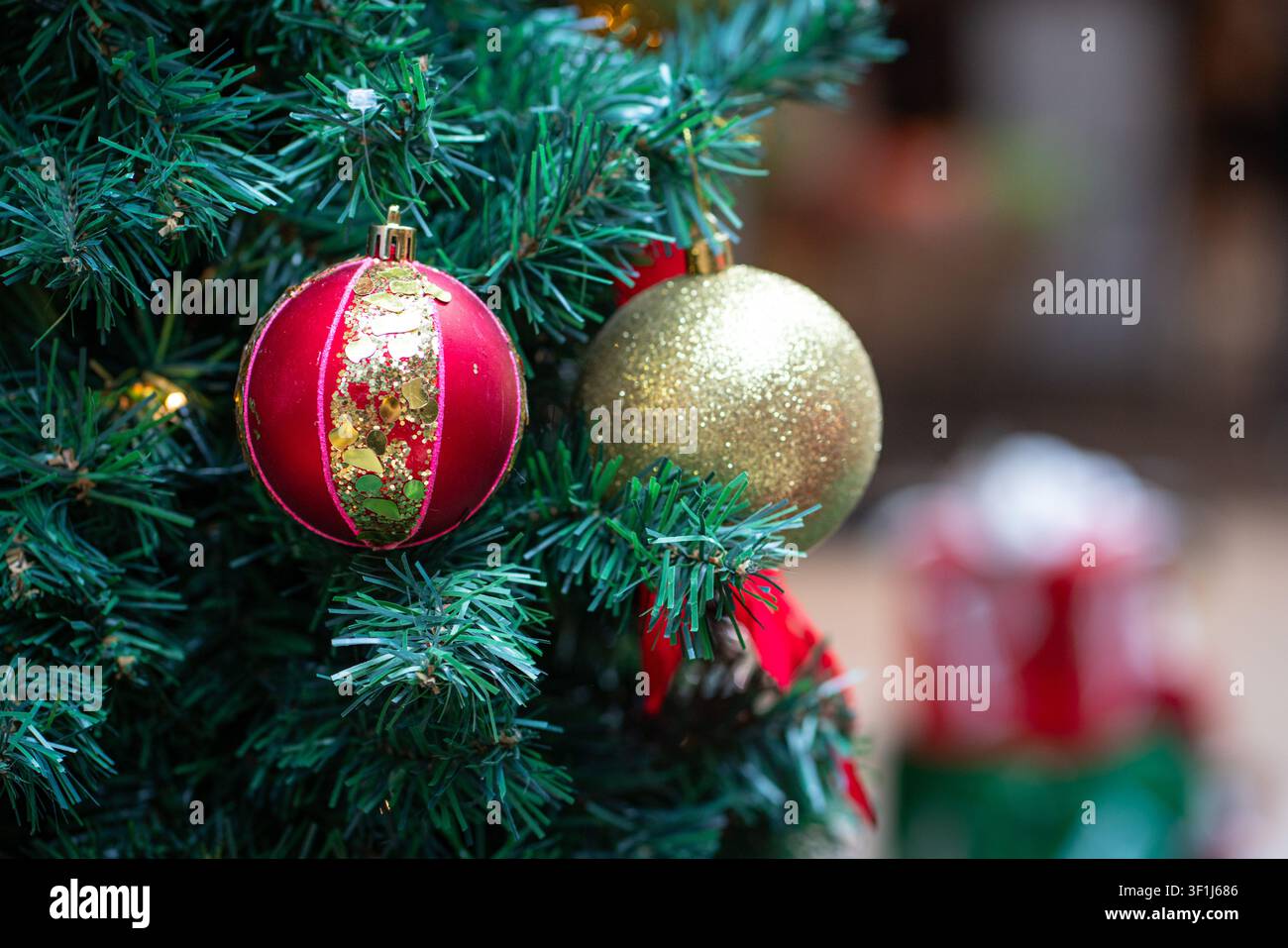 Palle di Natale appese a un albero con regali o doni sullo sfondo. Foto Stock