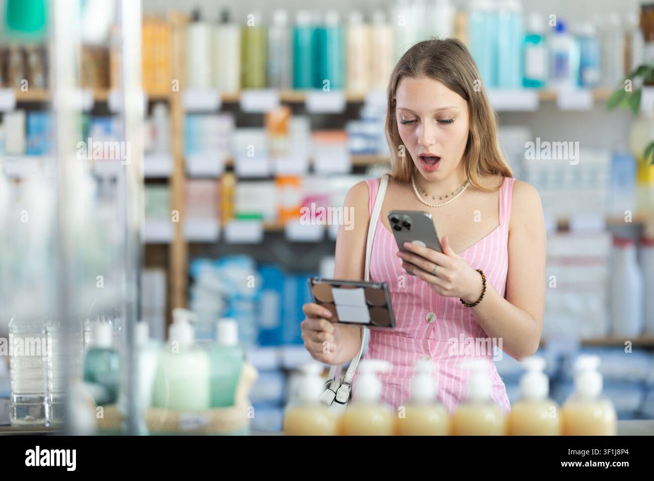 Ragazza in abiti estivi scansiona il codice sui cosmetici per controllare la data di scadenza Foto Stock
