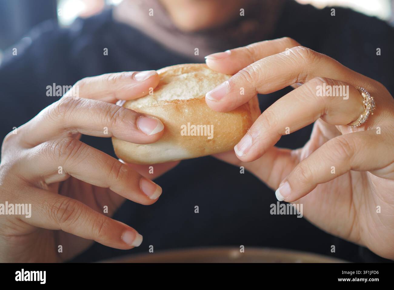 Mani che tengono un panino in un caffè Foto Stock