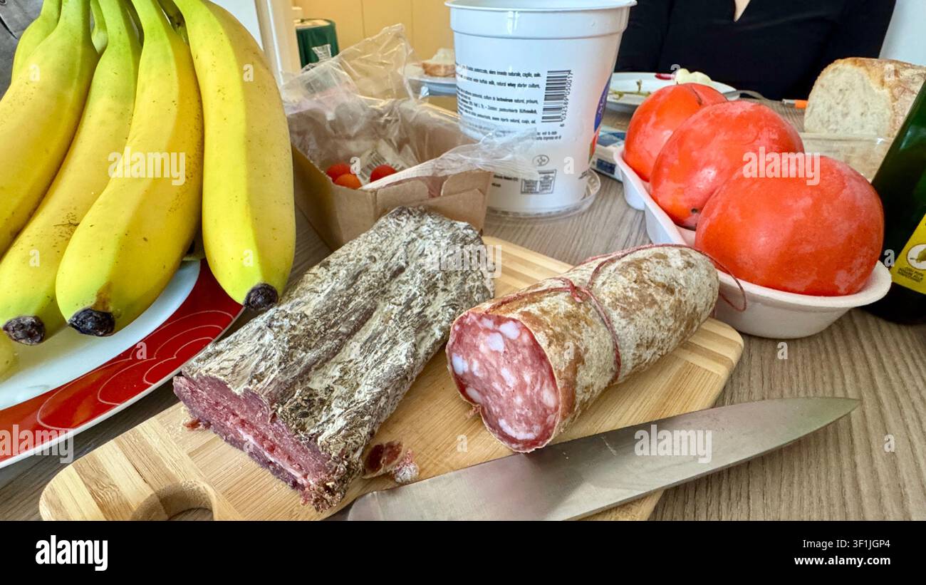 Tavolo apparecchiato con banane, salame e cachi - Immagine stock catturata con smartphone