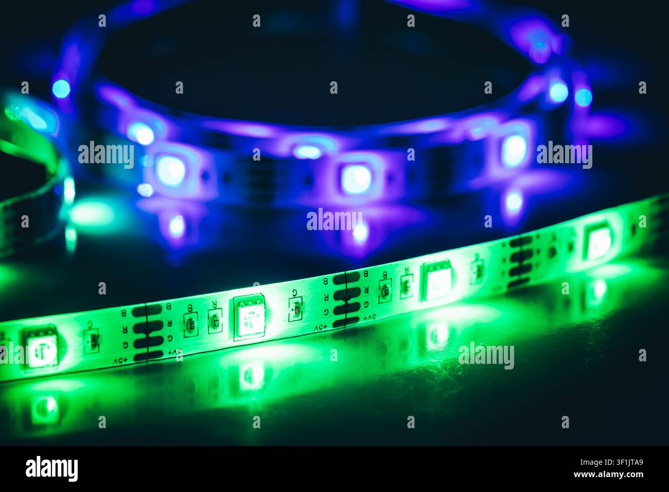 Luci LED verdi e viola che brillano su una superficie riflettente, primo piano Foto Stock