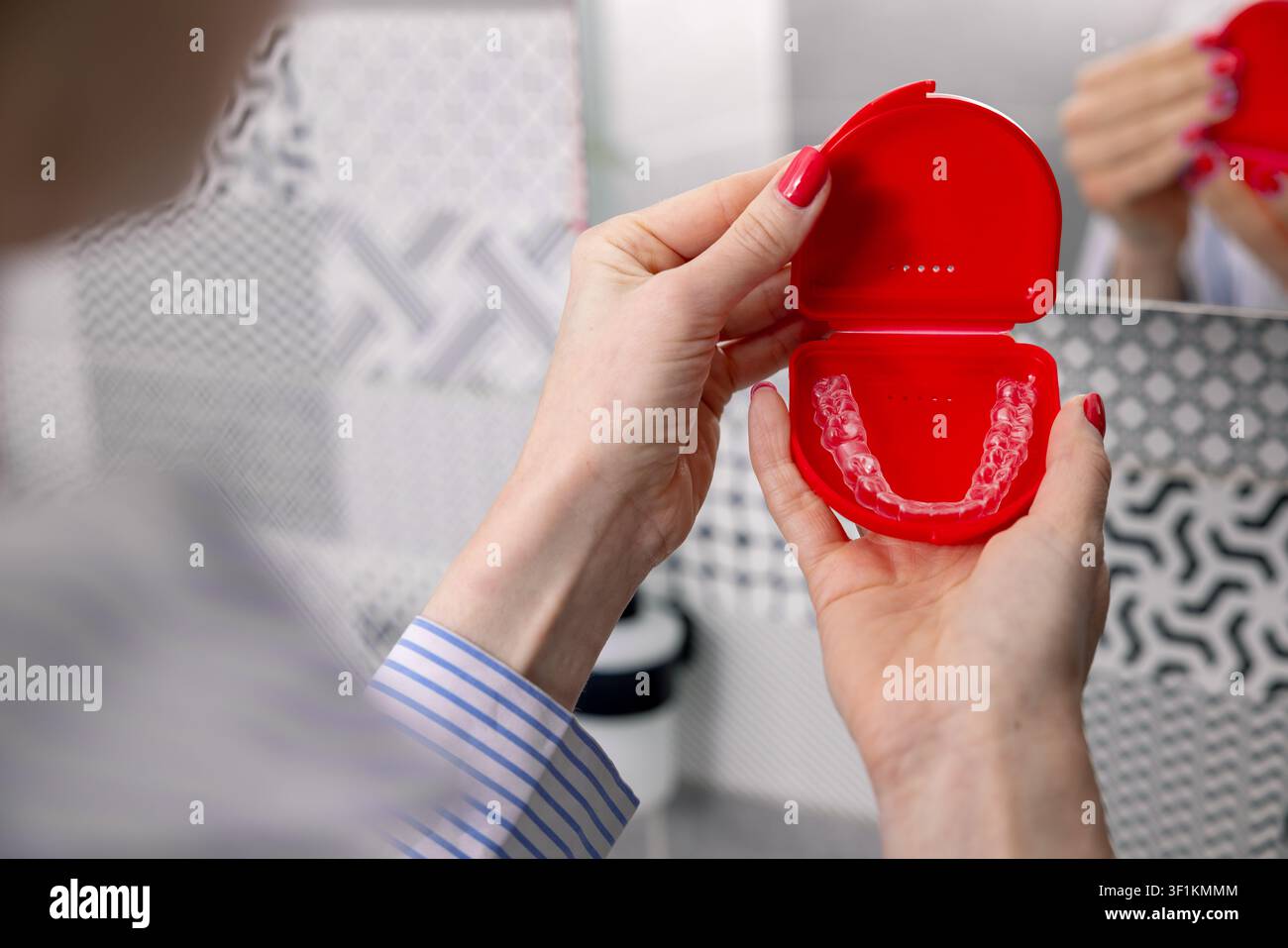 Donna che tiene una scatola con allineatori dentali trasparenti invisibili per la correzione dei denti Foto Stock