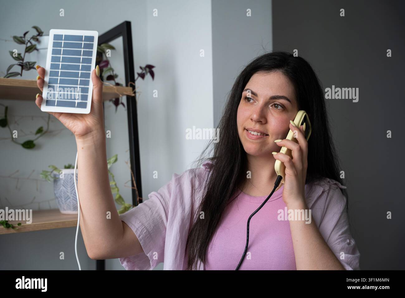 Giovane donna che discute le opzioni dei pannelli solari al telefono al chiuso. Consulenza sulle energie rinnovabili e assistenza clienti per le tecnologie verdi. Foto Stock