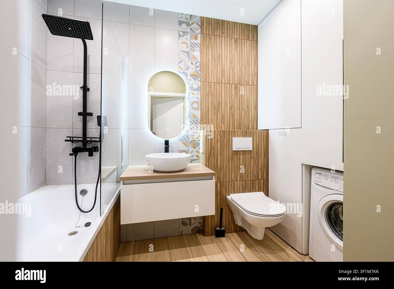 Bagno moderno con accenti in legno, rubinetteria bianca, doccia nera e uno specchio rotondo Foto Stock