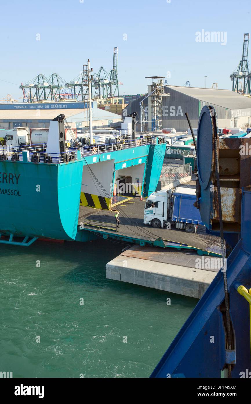 Camion che sale su una nave passeggeri con l'operatore portuale che dà indicazioni in una giornata soleggiata Foto Stock