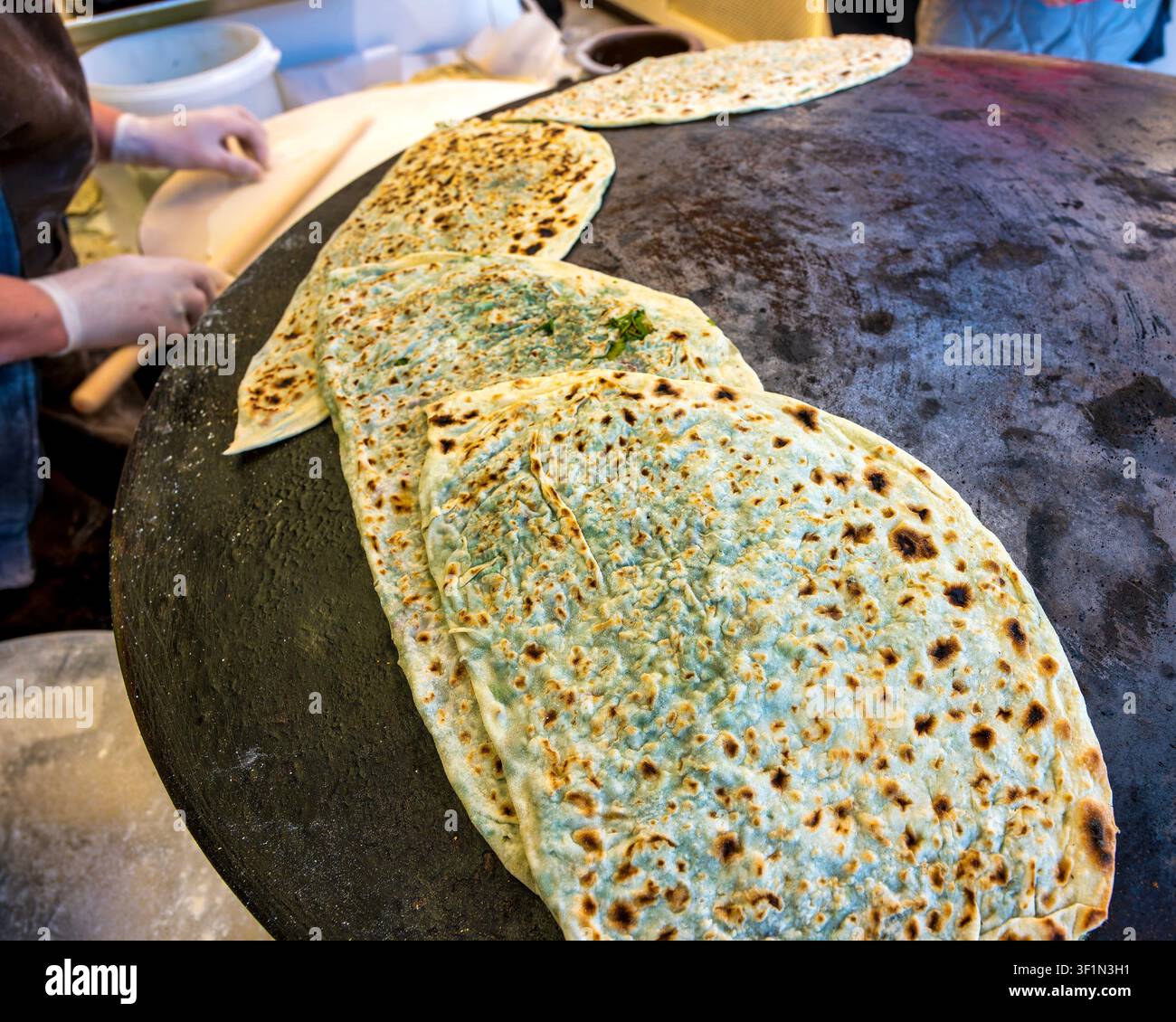 Focacce Qutab ripiene di erbe che cuociono su una piastra convessa saj a Baku, in Azerbaijan. Foto Stock