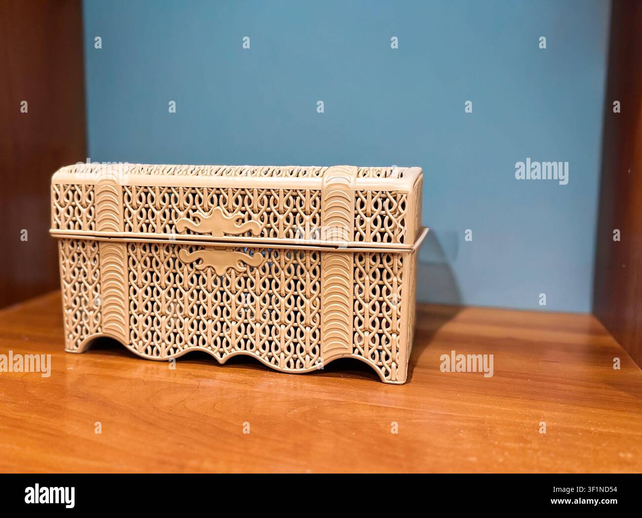 Uno scrigno per gioielli decorativo in plastica beige con intricati motivi a grata su uno scaffale di legno. - Immagine stock catturata con smartphone