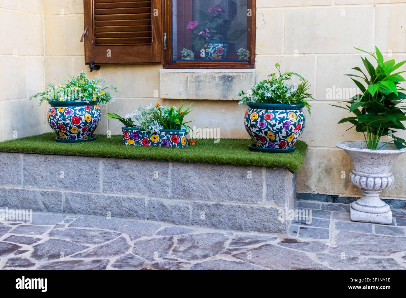 Vasi di fiori in ceramica sul davanzale della finestra di un cortile mediterraneo con piante in vaso colorate e vegetazione Foto Stock