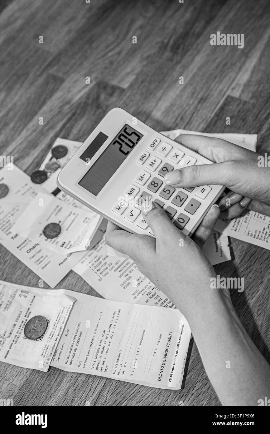 Calcolatrice bianca utilizzata per sommare le ricevute su carta per le finanze personali o la contabilità aziendale. La scena illustra il monitoraggio quotidiano delle spese Foto Stock