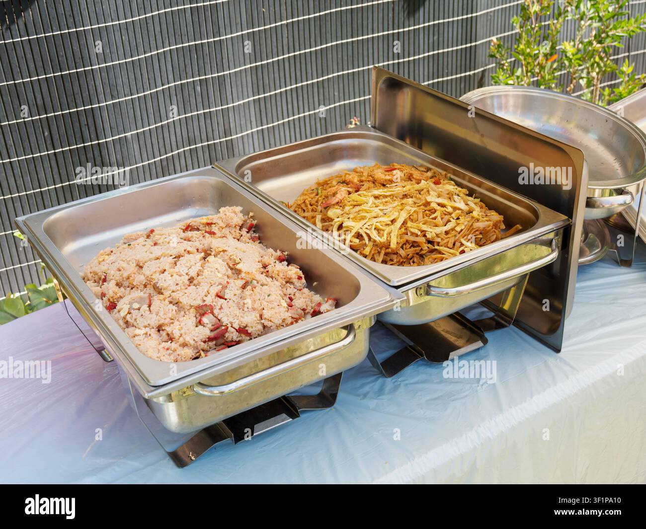 Buffet per catering all'aperto con riso condito e noodles fritti in pentole termiche in acciaio inossidabile Foto Stock