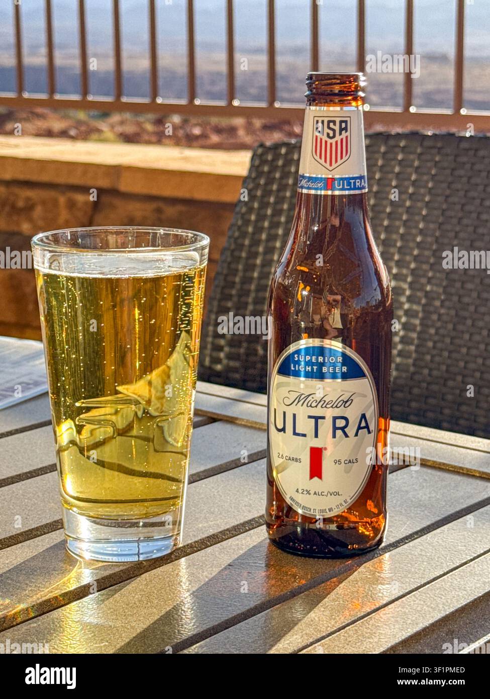Page, Arizona, USA - 30 giugno 2026: Bottiglia di birra leggera ipocalorica Michelob Ultra e un bicchiere pieno su un tavolo sulla terrazza di un hotel. - Immagine stock catturata con smartphone