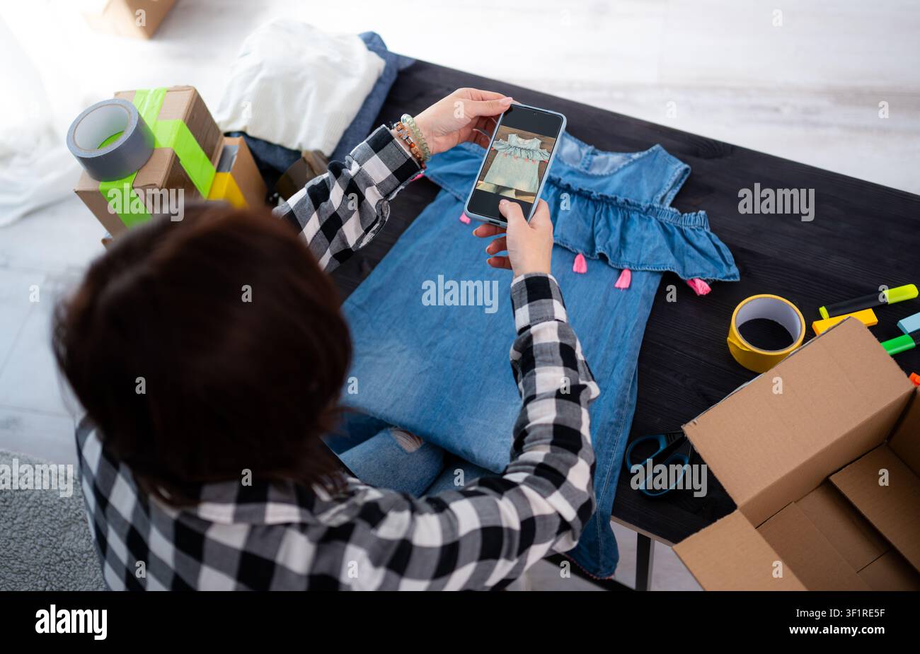 Ragazza che fotografa un vestito estivo per la vendita online di articoli usati Foto Stock
