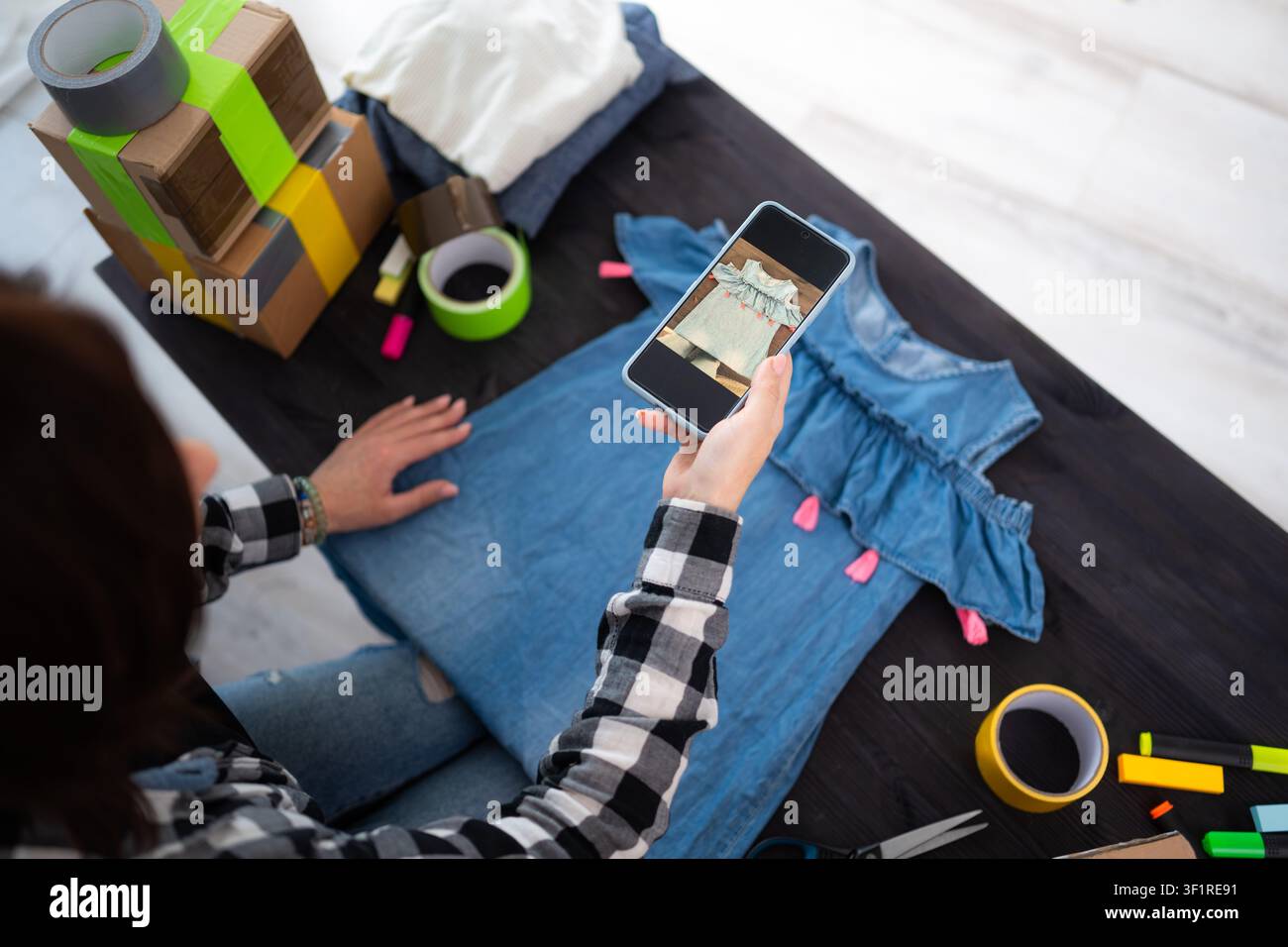 Ragazza che scatta una foto di un vestito estivo per inserzioni online di vendita di articoli usati Foto Stock