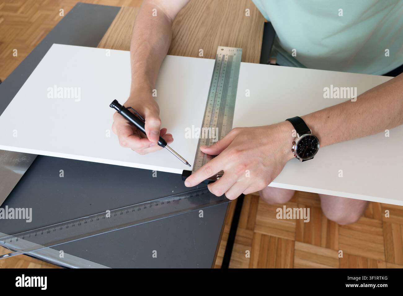 Un uomo misura e segna un pannello di mobili con un righello prima di tagliare durante un progetto di ristrutturazione fai-da-te. La pianificazione precisa migliora l'accuratezza Foto Stock