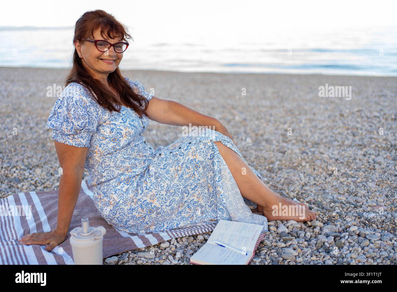 Donna che legge un libro sulla spiaggia Foto Stock