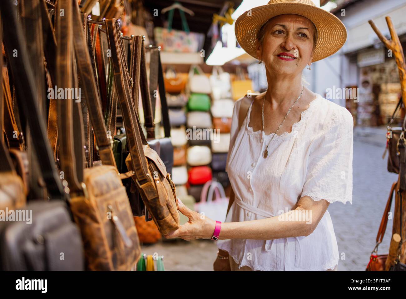 Turista anziana che acquista una borsa al mercato Foto Stock