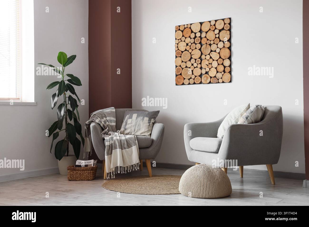 Interno moderno di soggiorno con due poltrone grigie, una grande pianta d'appartamento e un'arte murale unica in fetta di legno Foto Stock