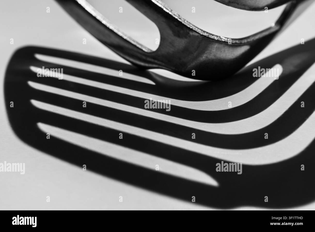 Il bordo della spatola a fessura proietta un'ombra a strisce curva in bianco e nero Foto Stock