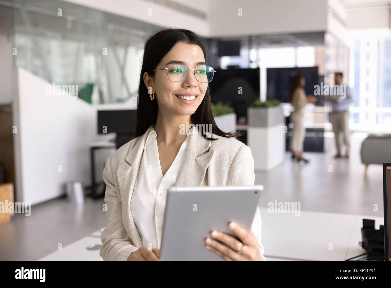 Donna attraente in piedi in un ufficio di coworking con un tablet digitale moderno Foto Stock