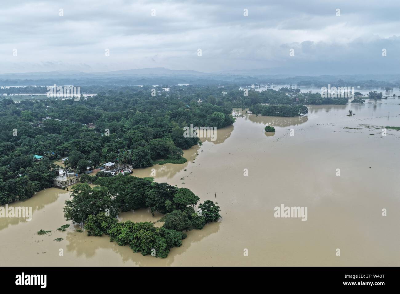 Satania, Bangladesh – 11 luglio 2026: Veduta aerea di un paesaggio allagato con alberi e case sommersi sotto un cielo nuvoloso. Foto Stock
