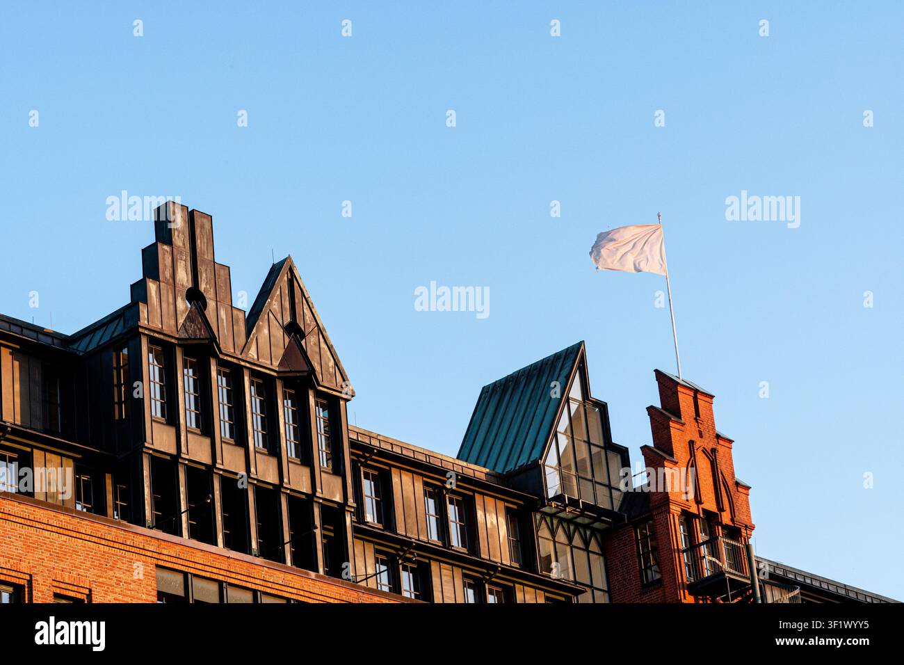Facciata di architettura storica in mattoni rossi con bandiera bianca e cielo blu Foto Stock