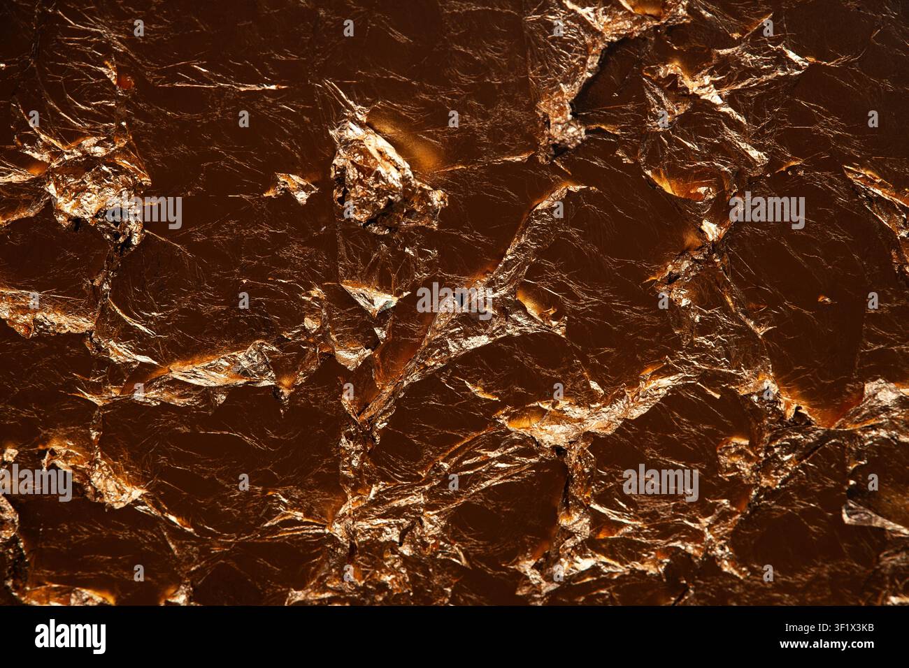 Sfondo astratto con texture di bronzo scuro composto da fogli metallici accartocciati e pezzi di rame invecchiati con ombre profonde e riflessi Foto Stock