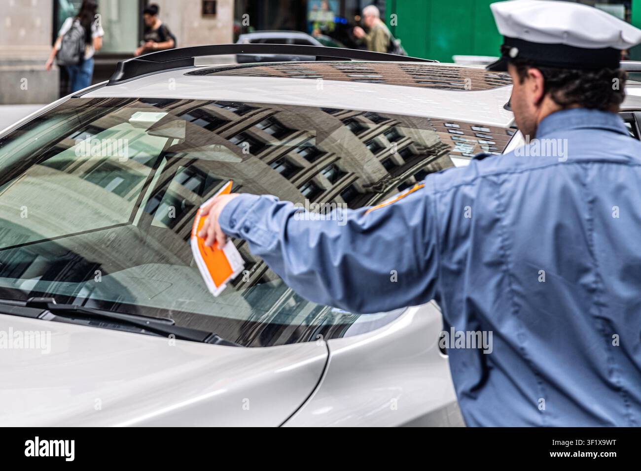 Un agente di controllo del traffico appoggia un biglietto di parcheggio sul parabrezza di un'auto a New York City. Foto Stock