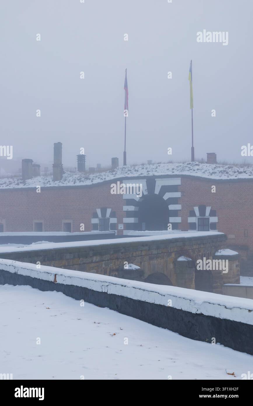 La fortezza di Mala Pevnost avvolta in una fitta nebbia invernale con la neve che copre il terreno Foto Stock