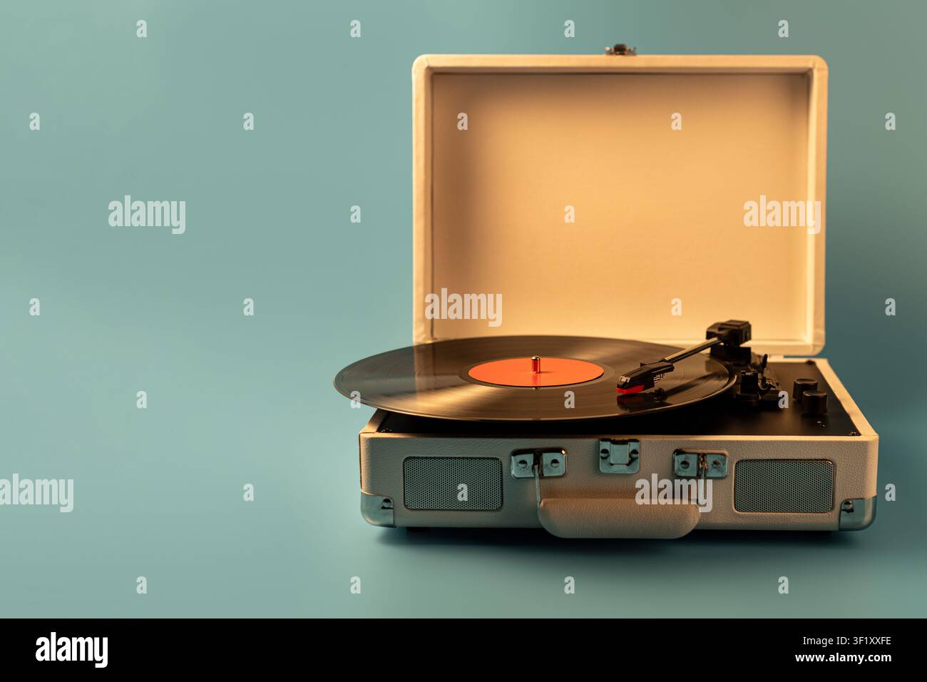 Un giradischi classico in stile valigia è aperto, mostrando un vinile nero con un'etichetta arancione e il braccio di lettura pronto per la riproduzione Foto Stock