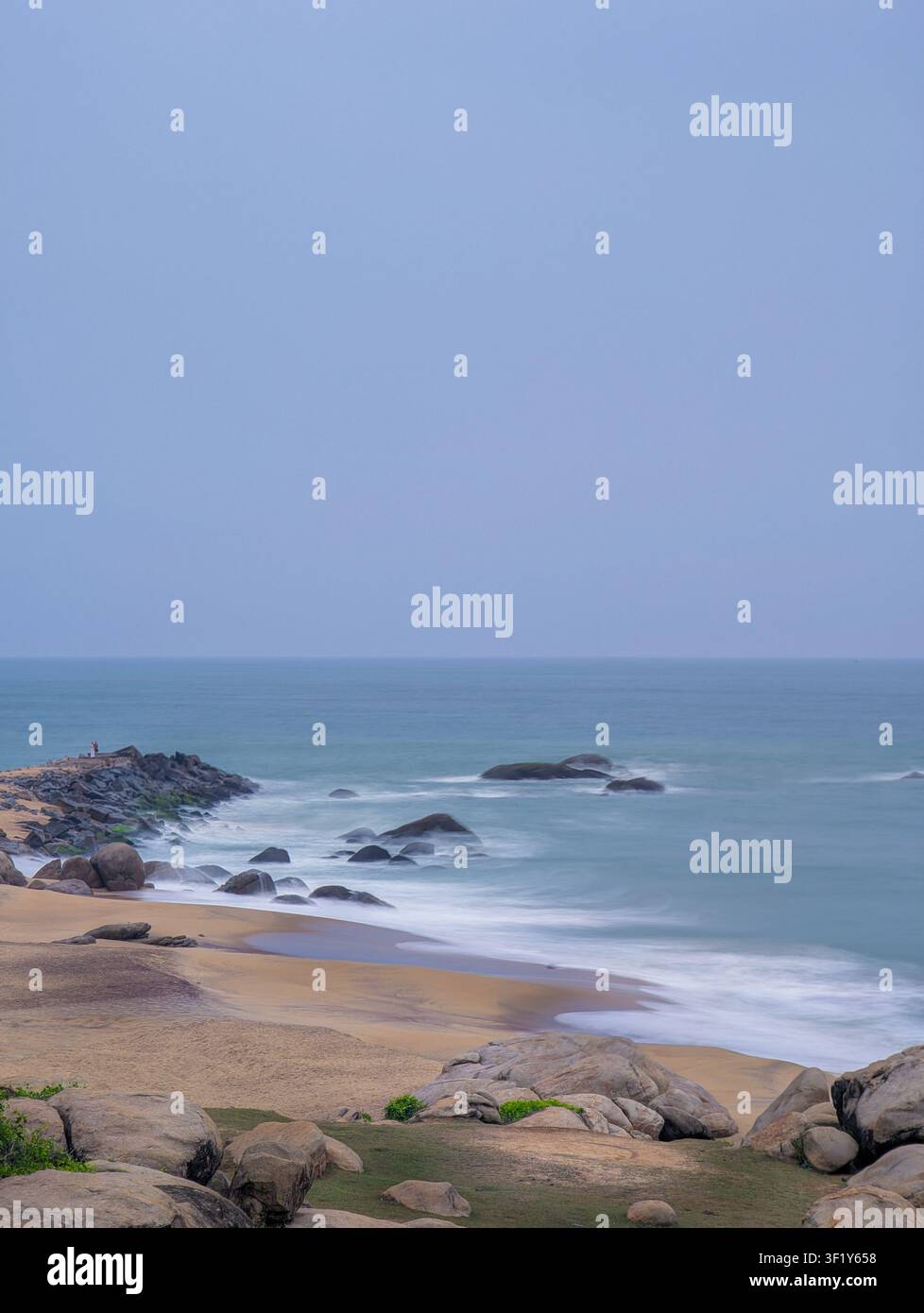 Esposizione lunga delle onde dell'oceano su una spiaggia sabbiosa rocciosa - Immagine stock catturata con smartphone