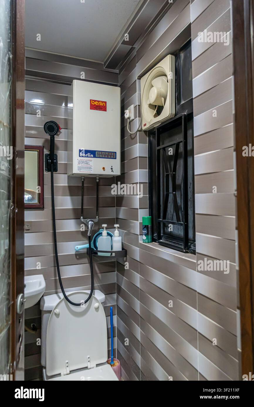 piccolo bagno e doccia combinati, pareti piastrellate orizzontali e scaldabagno tipici delle sistemazioni economiche, Chungking Mansions a Hong Kong Foto Stock