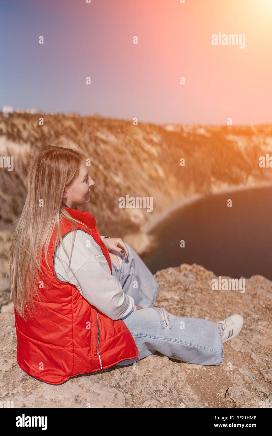 Donna sul ciglio di una scogliera che si affaccia sull'oceano durante il tramonto con spazio per il testo Foto Stock