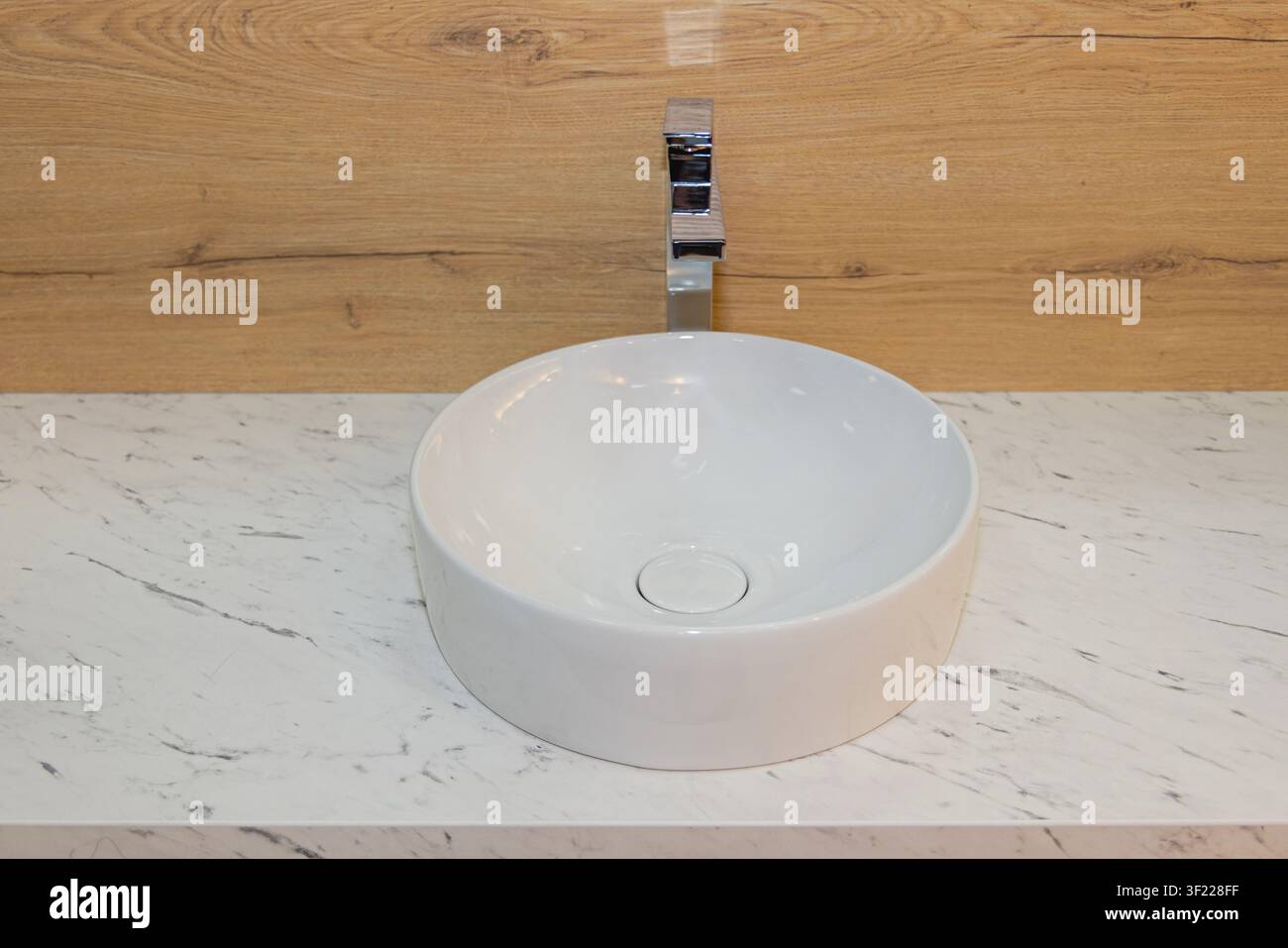 Lavandino rotondo in ceramica con rubinetto in acciaio inossidabile nel bagno moderno Foto Stock