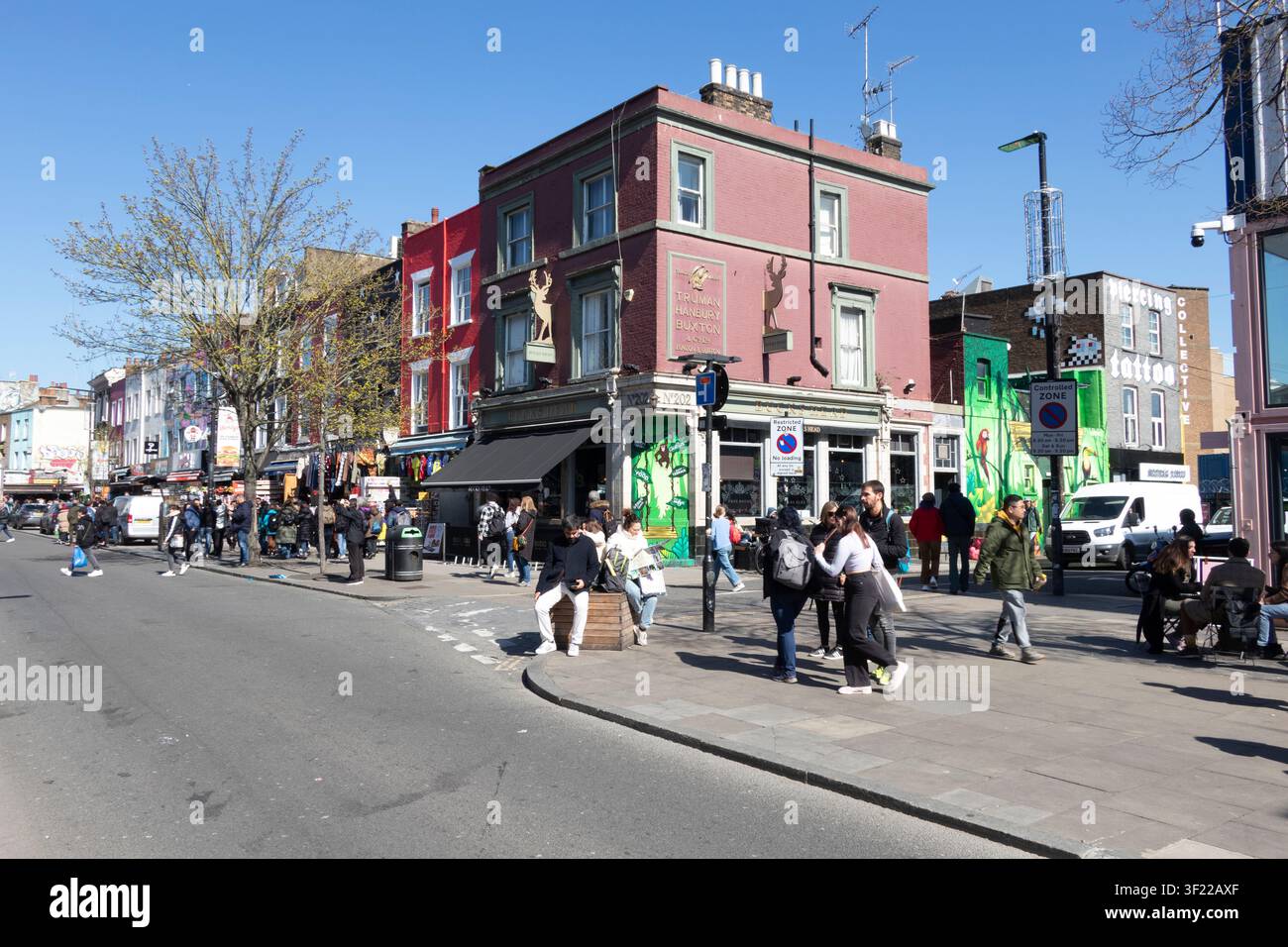Persone che camminano sul marciapiede vicino al pub Elephant Head all'angolo di Camden High Street in una giornata di sole, Camden Town, Londra, Inghilterra, Regno Unito. Foto Stock