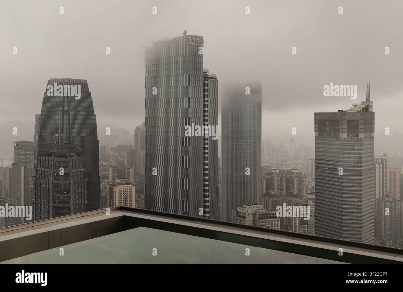 Chongqing, Cina - 8 giu 2026 - Una vista elevata ad angolo alto che si affaccia su un fitto gruppo di grattacieli moderni che perforano uno spesso strato di bassa quota Foto Stock