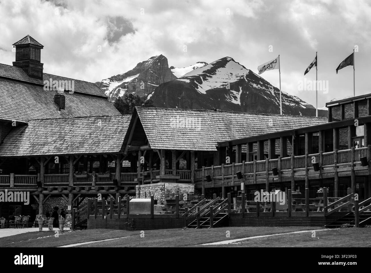 Vista in bianco e nero della Base Lodge del Lake Louise Ski Resort con picchi innevati che si ergono oltre gli edifici in legno nel Parco Nazionale di Banff Foto Stock